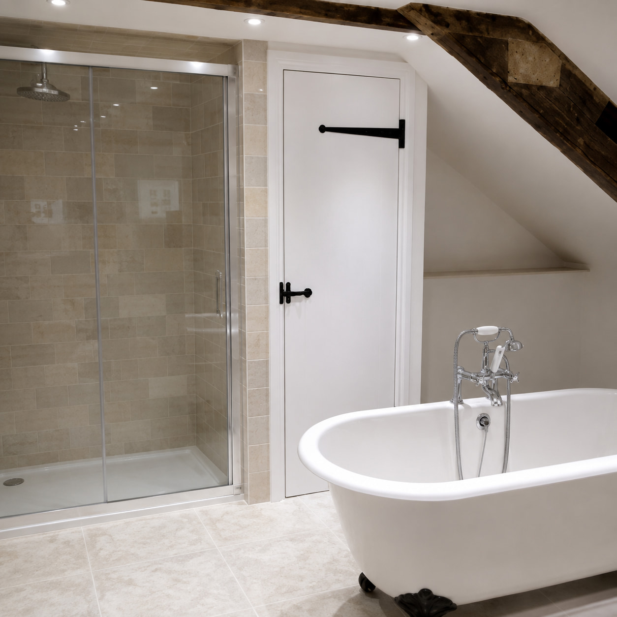 Modern bathroom with a white freestanding bathtub, glass-enclosed shower, beige tiled walls and floor, exposed wooden beam, and a white door with black hardware under a sloped ceiling.